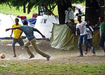 Como migranti giocano al pallone ai giardini della stazione di San Giovanni