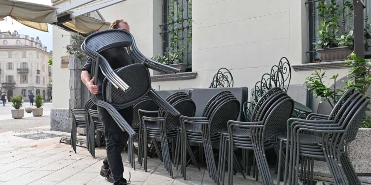 tavolini Un barista ripone delle sedie a causa delle chiusure