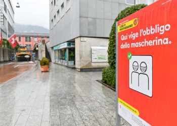 Una strada in Svizzera con un cartello di invito ad indossare la mascherina