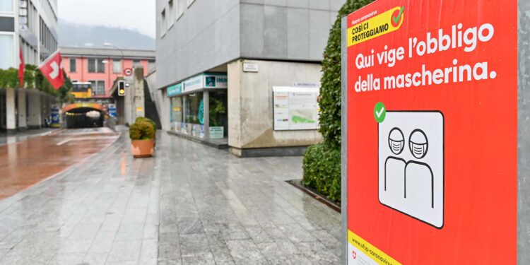 Una strada in Svizzera con un cartello di invito ad indossare la mascherina