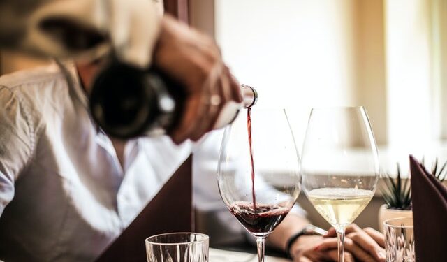 mano versa vino in un calice su un tavolo di un ristorante