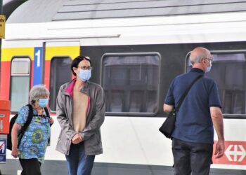 Persone con mascherina in attesa del treno