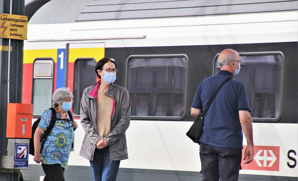 Persone con mascherina in attesa del treno