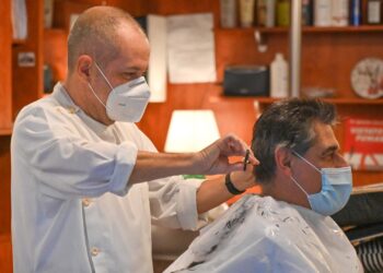 Un parrucchiere taglia i capelli a un cliente