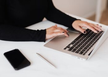 le mani di una donna sulla tastiera di un computer portatile