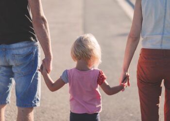 assegno unico universale. nella foto padre, bambina e madre si tengono per mano di spalle