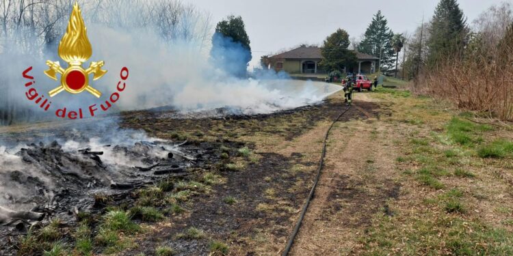 Incendio di una catasta di legna, vigili del fuoco in azione