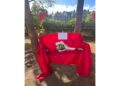 Il foglio su una panchina rossa con un mazzo di rose bianche