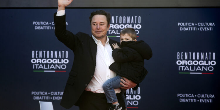 Il patron della Tesla sul palco di Atreju con uno dei figli