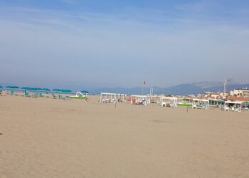 Ultimo sole richiama gitanti sulla costa. Ombrelloni in spiaggia