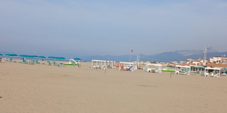 Ultimo sole richiama gitanti sulla costa. Ombrelloni in spiaggia